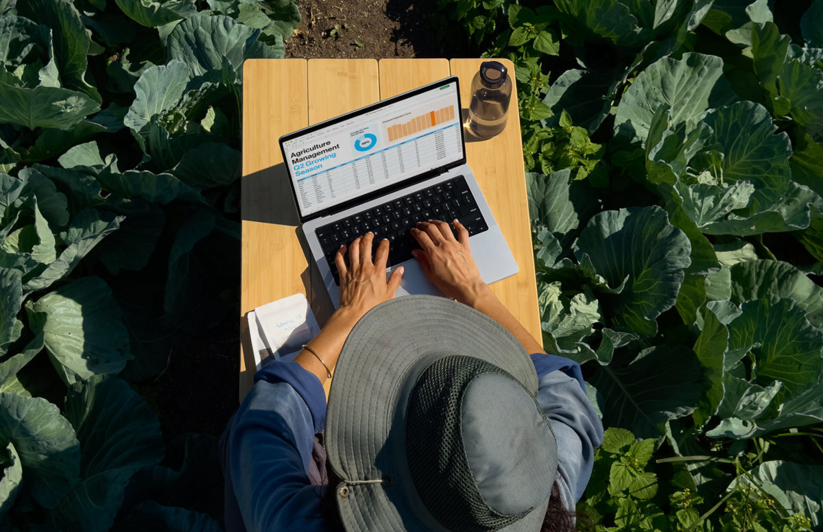 APPLE MacBook Pro układu scalonego Apple całą architekturę macOS integracja sprzętu z oprogramowaniem aktualizacje MacBooka Pro Touch ID czy apka Znajdź chroni przed wirusami i złośliwym oprogramowaniem - Osoba pracująca na laptopie wśród roślin, biurko w plenerze