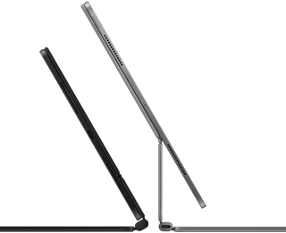 Dwa widoczne z boku smukłe iPady Pro podłączone do klawiatur Magic&nbsp;Keyboard, jednej w kolorze gwiezdnej czerni, nachylonej i półotwartej, z głośnikami i portem USB‑C, i drugiej w kolorze srebrnym, otwartej i nachylonej tak, że widać konstrukcję wspornika, głośników i mikrofonu