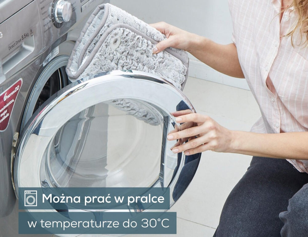 Osoba wkłada szarą, miękką poduszkę do pralki. Na obrazie widoczny jest tekst: \'Można prać w pralce w temperaturze do 30°C\'.