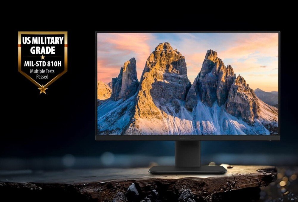 Komputer All in One ASUS ExpertCenter PM670KA-BPE012X Monitor wyświetlający zdjęcie wysokich i skalistych szczytów górskich o zachodzie słońca z umieszczonym po lewej stronie złotym godłem z napisem 'US MILITARY GRADE MIL-STD 810H', wytrzymałość, testy, obudowa