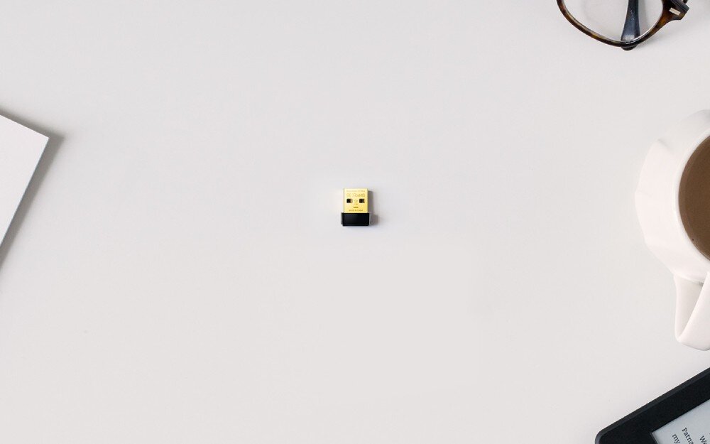 Komputer MAD DOG BF-A01DR16 Mały adapter USB z czarną podstawą i złotą końcówką leżący na białym biurku, karta sieciowa Wi-Fi