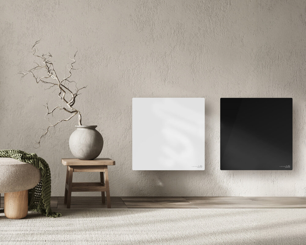 GRZEJNIK ELEKTRYCZNY AENO PREMIUM ECO SMART QUADRO 500W AGH0012S APP CZARNY Na ścianie umieszczono dwa minimalistyczne panele grzewcze — biały i czarny — tworzące elegancki kontrast w spokojnym, naturalnym wnętrzu. Obok stoi stolik z ceramiczną wazą i suchą gałązką, które podkreślają harmonijny, stonowany charakter aranżacji eleganckie wzornictwo estetyka funkcjonalność podczerwień cienki szklany panel dekoracja