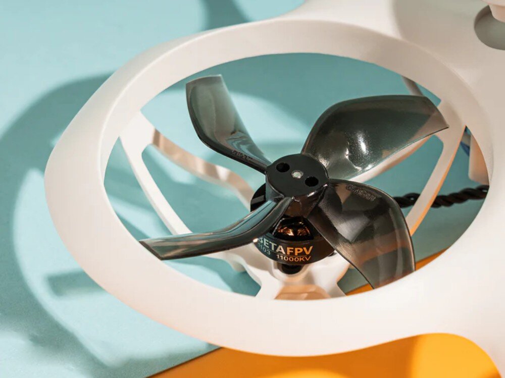Dron BETAFPV Cetus X Zbliżenie na czarne czteropłatowe śmigło i silnik bezszczotkowy w białej ramie