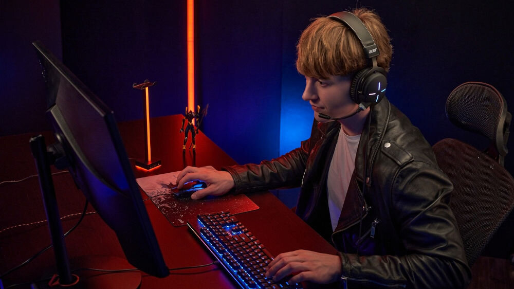 Słuchawki ACER Nitro II NHW200 Nauszne prezentacja słuchawek podczas korzystania chłopak siedzący przy komputerze w ciemnym pokoju wbudowany mikrofon bez szumów gry nauka zdalna rozmowy