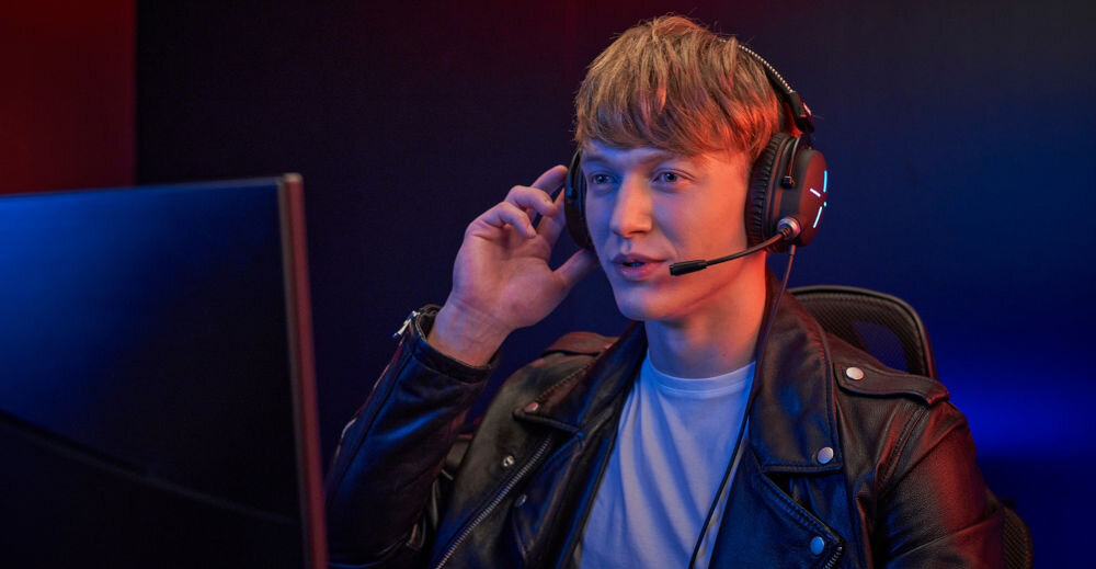 Słuchawki ACER Nitro II NHW200 Nauszne prezentacja słuchawek podczas korzystania chłopak siedzący przy komputerze w ciemnym pokoju miękkie nauszniki wygodne wsparcie wiele godzin bez zmęczenia