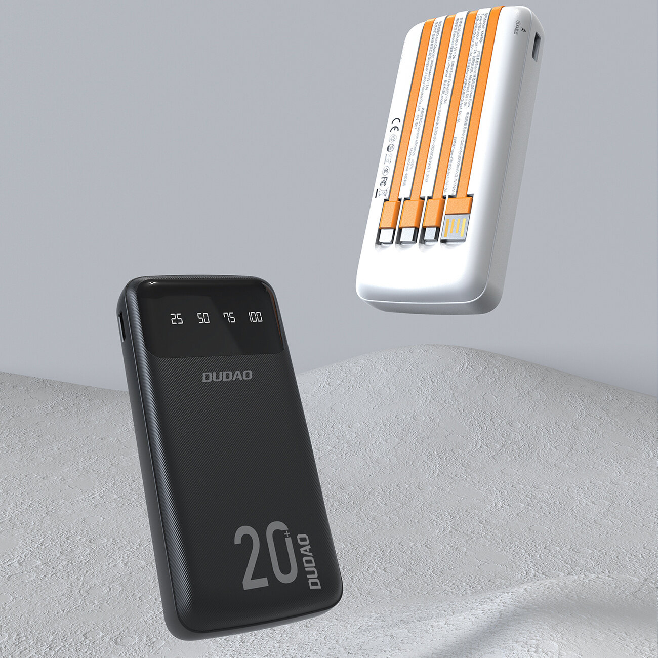 Na obrazie widoczny jest czarny powerbank z napisem \'DUDAO\' i oznaczeniami procentowymi 25, 50, 75, 100. Obok znajduje się biały powerbank z trzema wbudowanymi kablami w kolorze pomarańczowym.