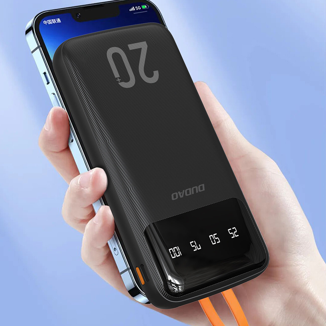 Czarny powerbank z wyświetlaczem cyfrowym pokazującym stan naładowania, trzymany w dłoni. Na obudowie widoczne jest logo \'Dudao\'.