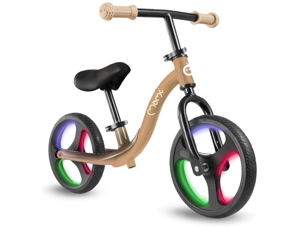 Rowerek biegowy MOMI Isoka Beżowy rowerek na białym tle widoczny od przodu pod skosem włączone światła na kołach koła ze wbudowanymi światłami LED aktywują się automatycznie podczas jazdy działają na zasadzie mechanizmu dynamo nie wymagają baterii ani ładowania efektowne podświetlenie kół przy każdym ruchu