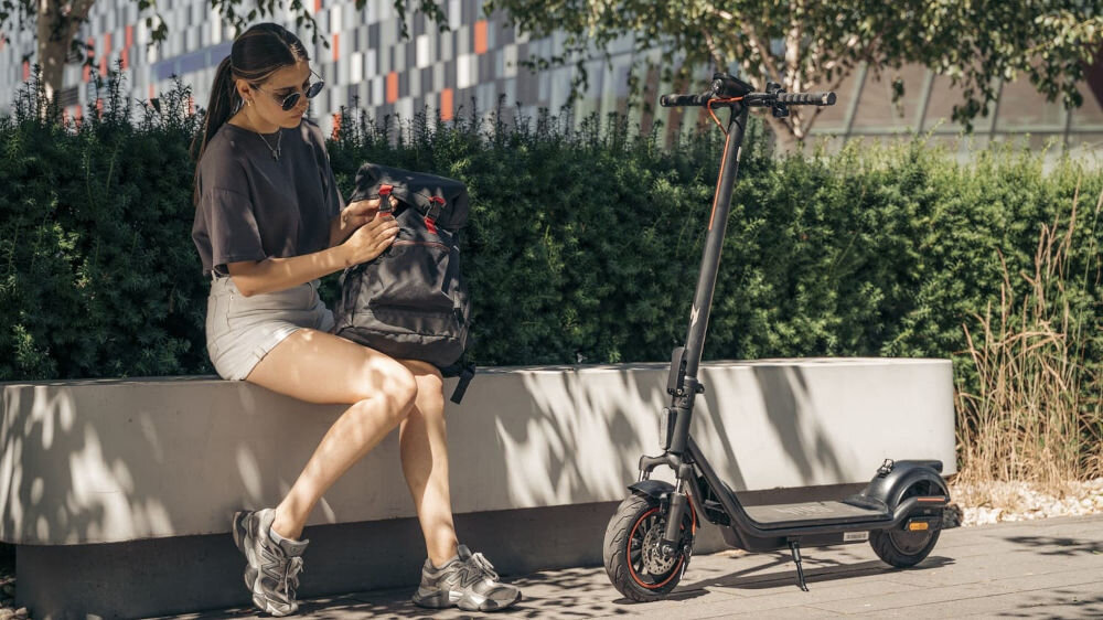 Hulajnoga elektryczna ACER Nitro Series 4 Select 50km 400W Amortyzacja 10 Czarny osoba siedząca na ławce koło hulajnogi try tryby kontrola komfort