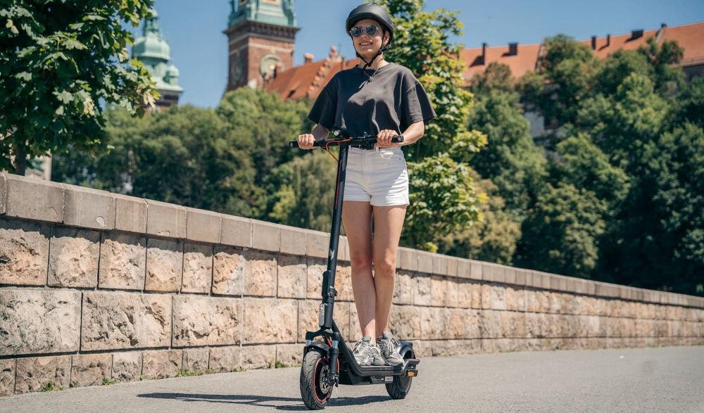 Hulajnoga elektryczna ACER Nitro Series 4 Select 50km 400W Amortyzacja 10 Czarny osoba w kasku jadąca na hulajnodze tylny silnik silnik 400W moment obrotowy nachylenie terenu pojemna bateria zasięg