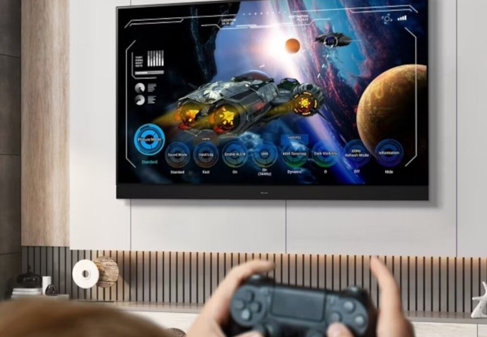 PANASONIC TV65W95BEG Game Control Board szybka konfiguracja konsoli, telewizor zawieszony na ścianie, osoba trzymająca kontroler w ręku