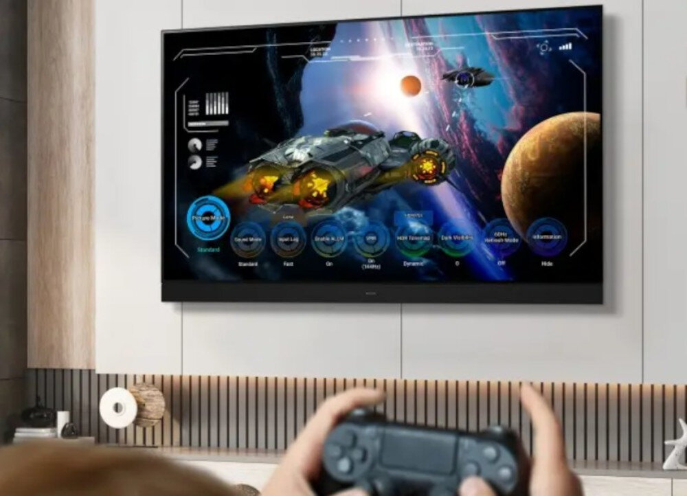 PANASONIC TV-65Z95BEG Game Control Board HDMI konfiguracja gry, telewizor zawieszony na ścianie, osoba trzymająca kontroler w ręku