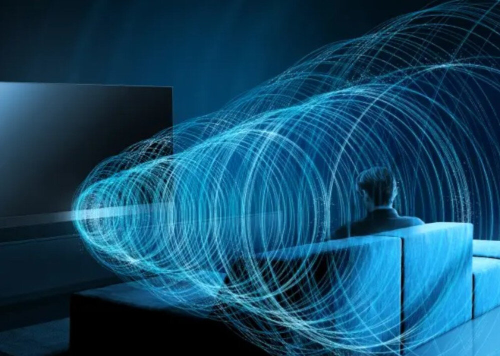 Telewizor PANASONIC TV-65Z95BEG głośniki Array Beam Forming dźwięk, osoba siedząca na kanapie otoczona dźwiękiem