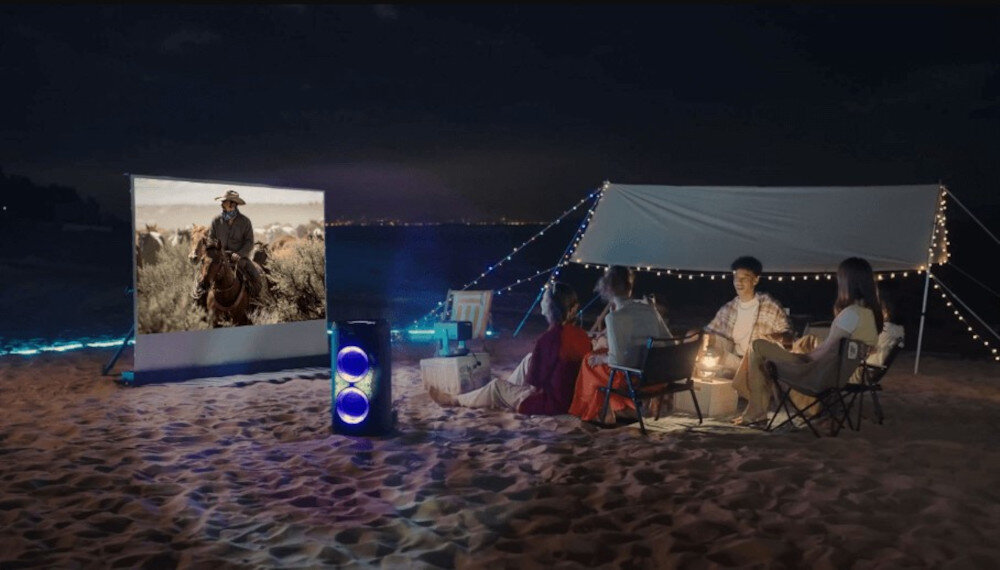 Power Audio HISENSE Party Thunder Auracast łączenie głośników bezprzewodowo, głośnik stojący na plaży, ludzie biwakujący nad morzem