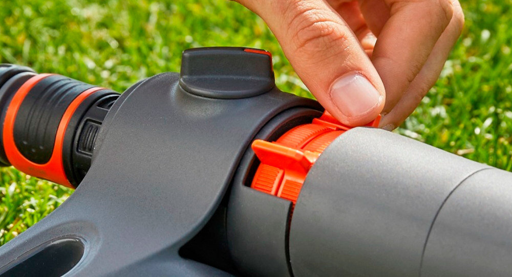 Zraszacz GARDENA Aquazoom S 18710-20 trawnik zbliżenie na suwak do regulacji osoba trzyma suwak w palcach regulacja za pomocą suwaka regulacja zasięgu od 3 do 15 metrów ułatwia codzienne użytkowanie skraca czas potrzebny na przygotowanie zraszacza do pracy