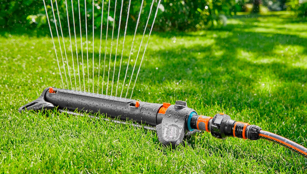 Zraszacz GARDENA Aquazoom S 18710-20 trawnik zraszacz na trawniku w tle drzewa kwiaty możliwość regulacji zasięgu i szerokości pracy rozprowadza wodę równomiernie eliminuje problem przesuszeń i nadmiernego nawodnienia oszczędność wody