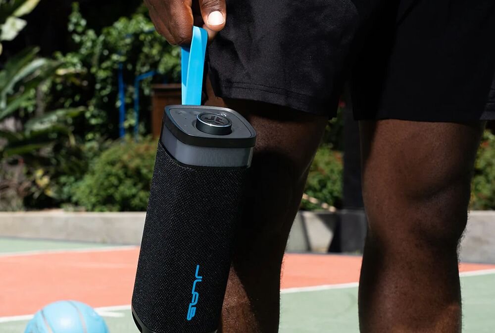 Głośnik mobilny JLAB Jbuds Party czas pracy 12 godzin akumulator 5000 mAh USB-C, osoba trzymająca głośnik za pasek