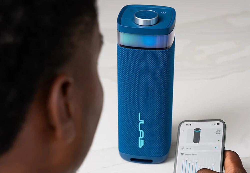 Głośnik mobilny JLAB Jbuds Party aplikacja sterowanie EQ4 ustawienia dźwięku, głośnik stojący na blacie, osoba ustawiająca dźwięk w aplikacji na smartfonie