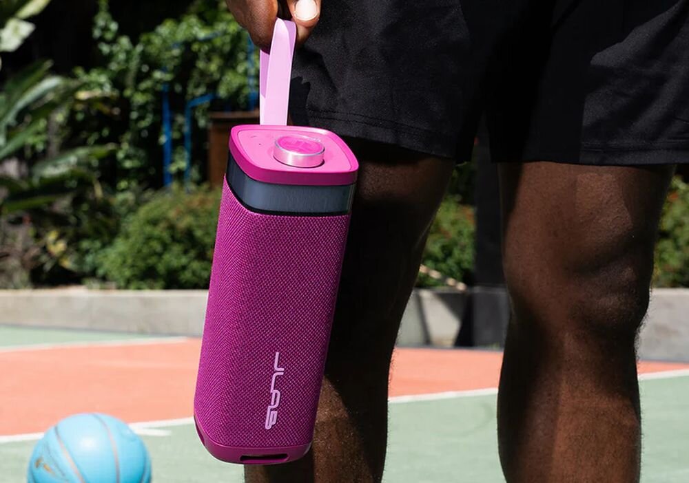 Głośnik mobilny JLAB Jbuds Party czas pracy 12 godzin akumulator 5000 mAh USB-C, osoba trzymająca głośnik za pasek