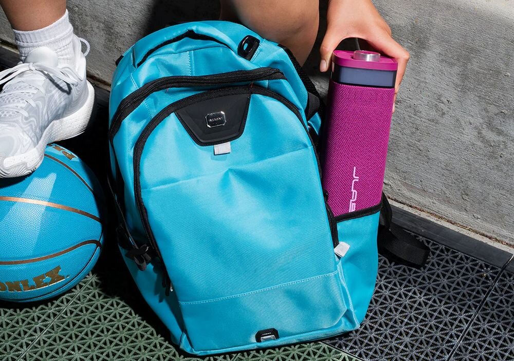 Głośnik mobilny JLAB Jbuds Party podświetlenie RGB efekty świetlne imprezowe, osoba wkładająca głośnik do plecaka