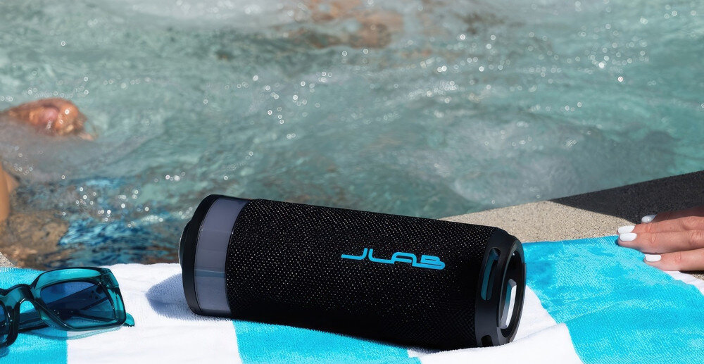 Głośnik JLAB Go Party podświetlenie RGB, sterowanie kolorami i wzorami przez aplikację, głośnik leżący na ręczniku plażowym