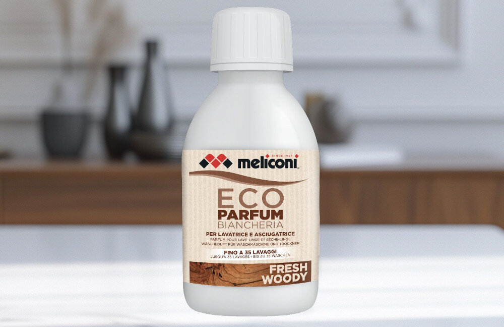 KROPLE ZAPACHOWE MELICONI Na pierwszym planie widać butelkę Meliconi ECO PARFUM w wariancie Fresh Woody ustawioną w domowym wnętrzu. Subtelne, rozmyte tło eksponuje produkt i podkreśla jego przeznaczenie do codziennego użytku do pralki i suszarki 