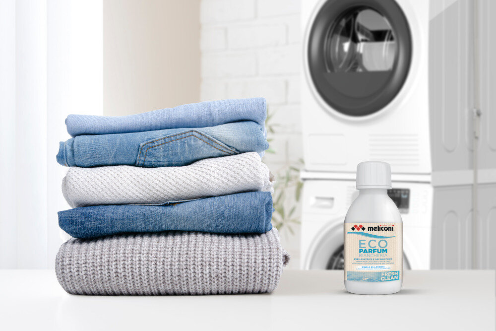 KROPLE ZAPACHOWE MELICONI Obok starannie złożonego stosu ubrań znajduje się butelka Meliconi ECO PARFUM w wariancie Fresh Clean. Scena podkreśla efekt działania produktu — świeżą i zadbaną odzież po praniu nuty mydlane Długotrwały intensywny zapach świeżość ubrań nuty mydlane zapach sosny eukaliptusa świeżość na długo