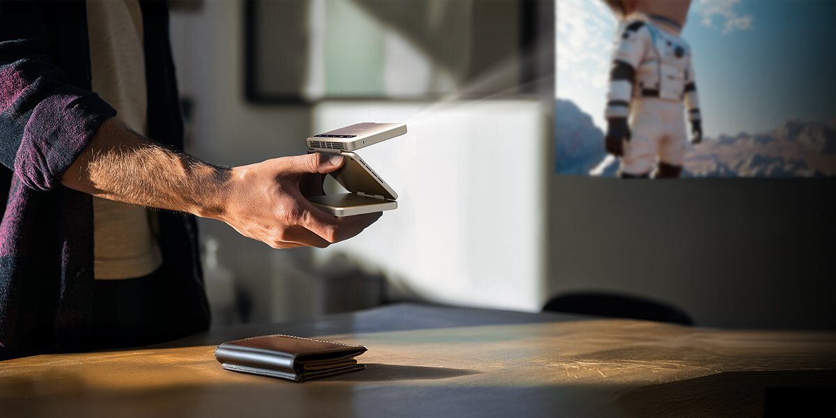 Projektor AURZEN Zip Tri-Fold Mini HD mobilne kino ogrodowe prezentacje, osoba trzymająca projektor w ręku