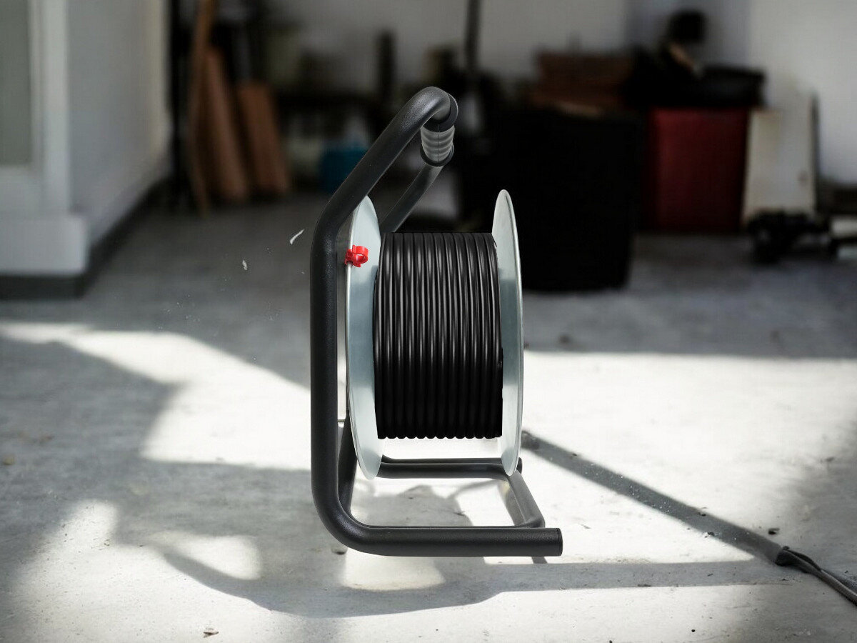 Przedłużacz bębnowy BORBY BY-02-36553 (40 m), praca, przewód, gniazda, trwałość, przedłużacz od boku frontem na wprost z nawiniętym kablem, w tle trwają prace remontowo-budowlane