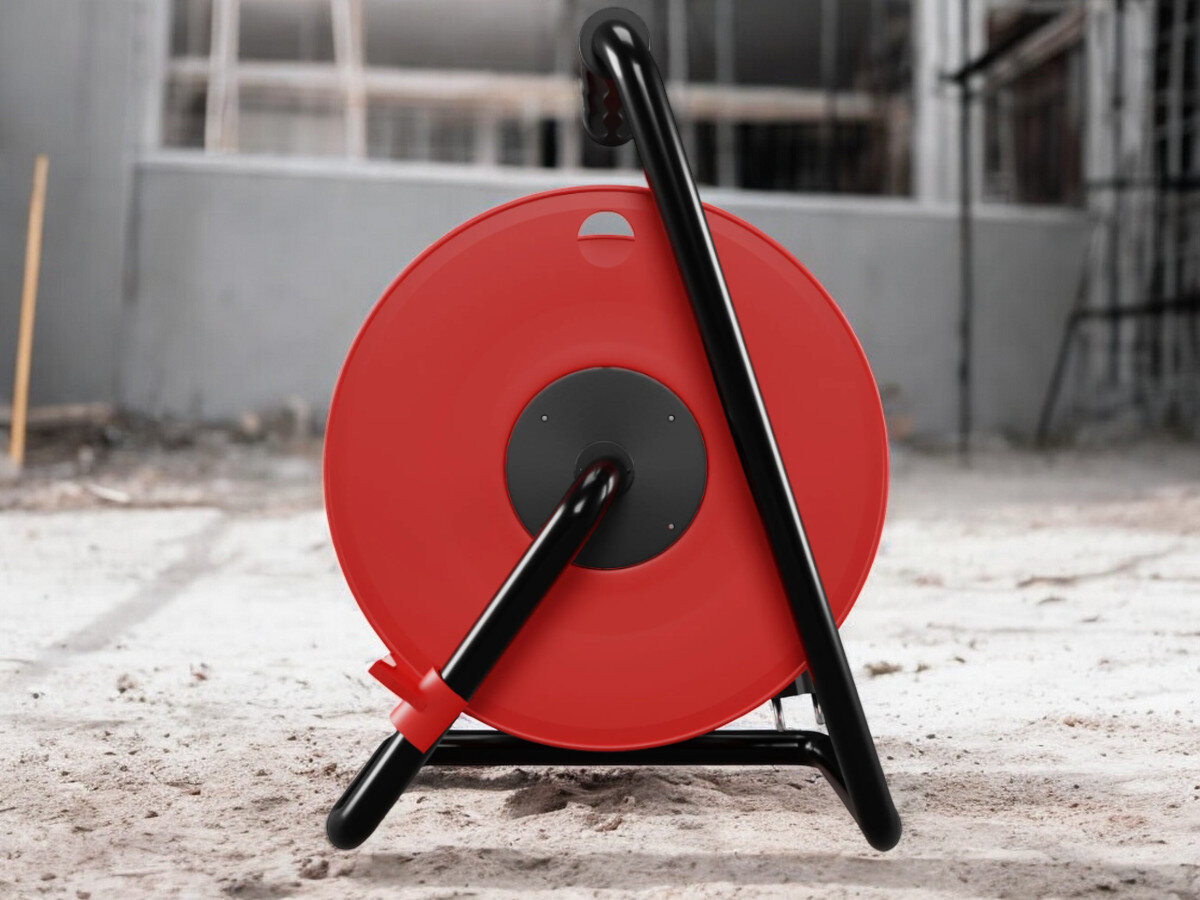 Przedłużacz bębnowy BORBY BY-02-36607 (25 m), gumowa, izolacja, IP44, blokada, nieruchome, przedłużacz od tyłu pionowo frontem na wprost, w tle trwająca prace remontowo-budowlane