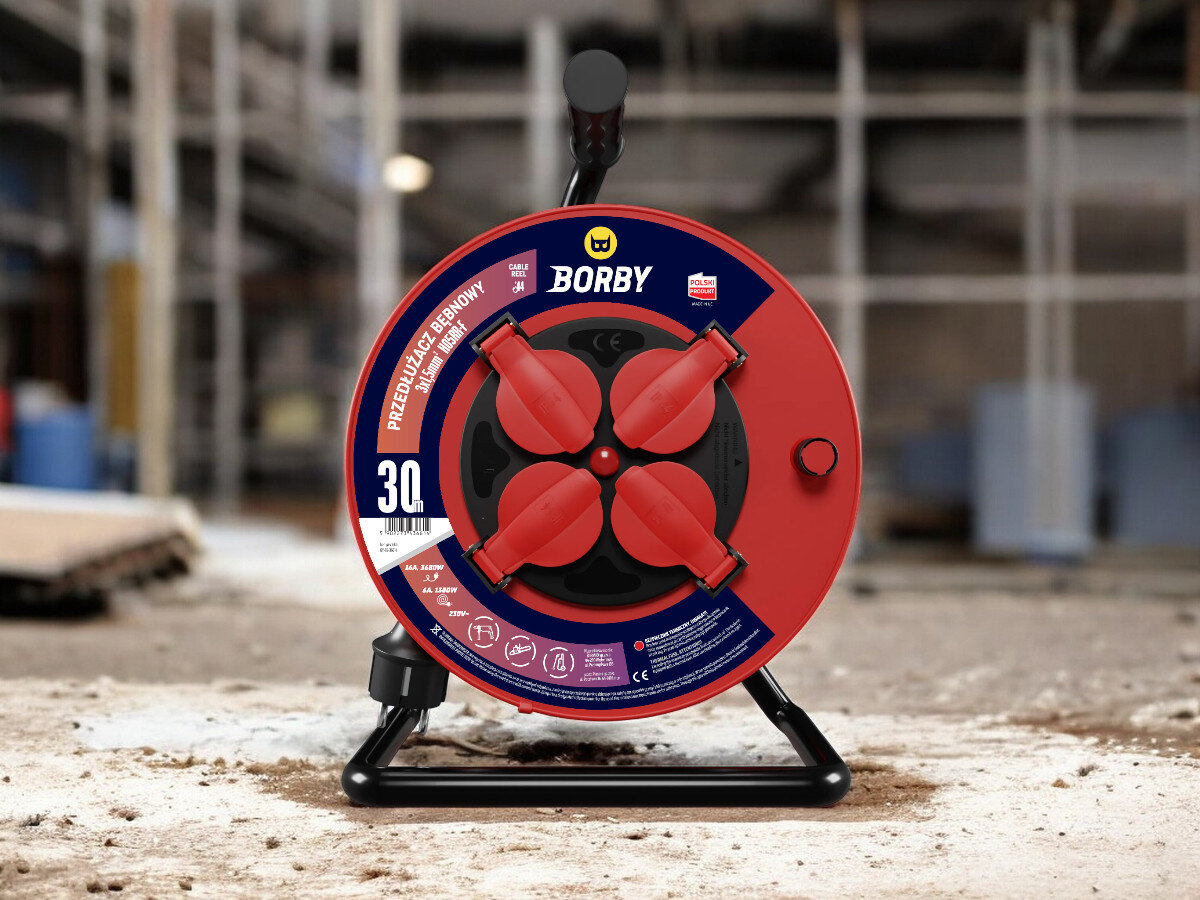 Przedłużacz bębnowy BORBY BY-02-36614 (30 m), solidne, odległość, zasięg, dystans, przedłużacz frontem na wprost z 4 wejściami stoi, w tle trwają prace remontowo-budowlane