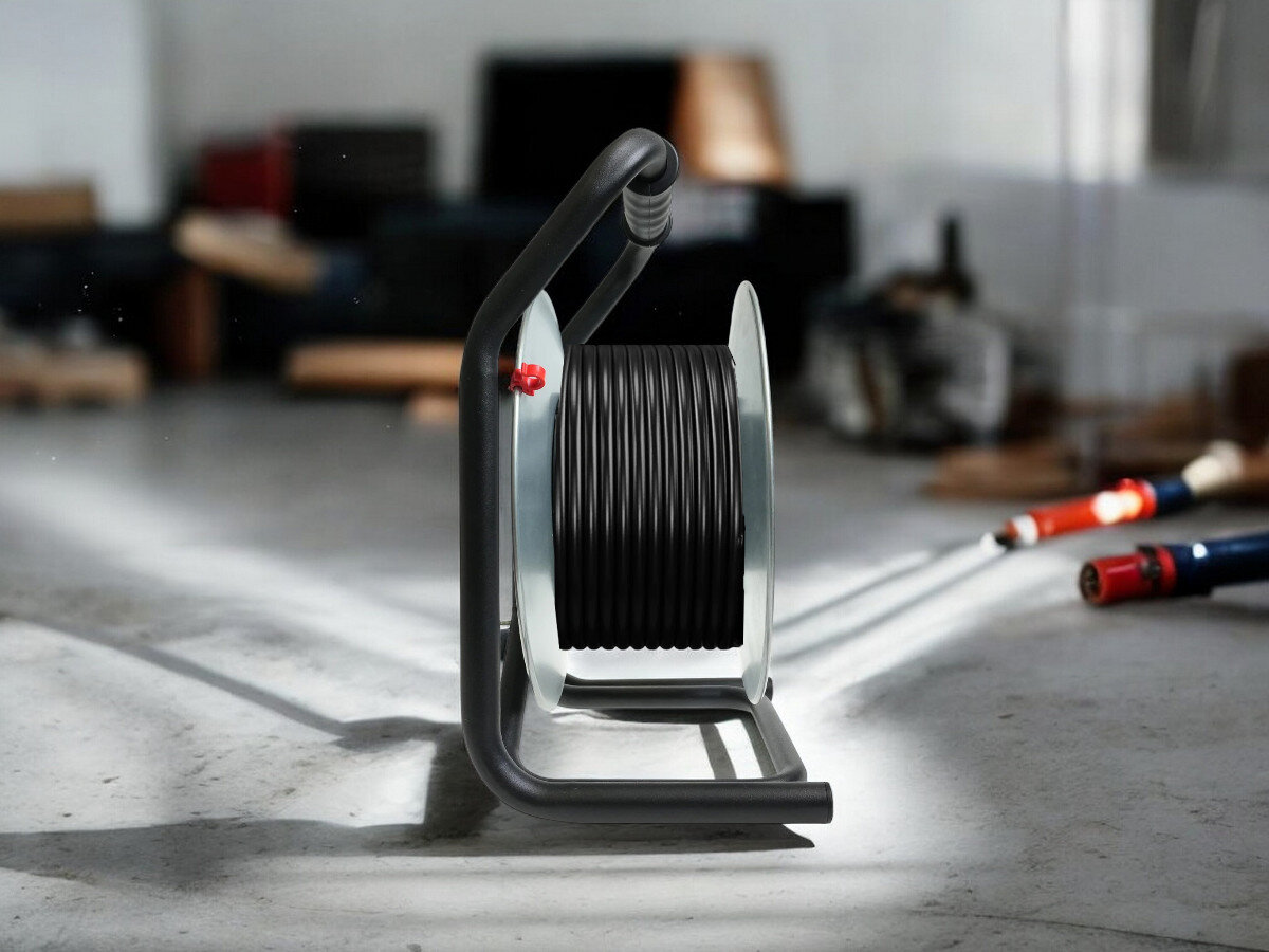 Przedłużacz bębnowy BORBY BY-02-36577 (50 m), praca, przewód, gniazda, trwałość, przedłużacz od boku frontem na wprost z nawiniętym kablem, w tle trwają prace remontowo-budowlane