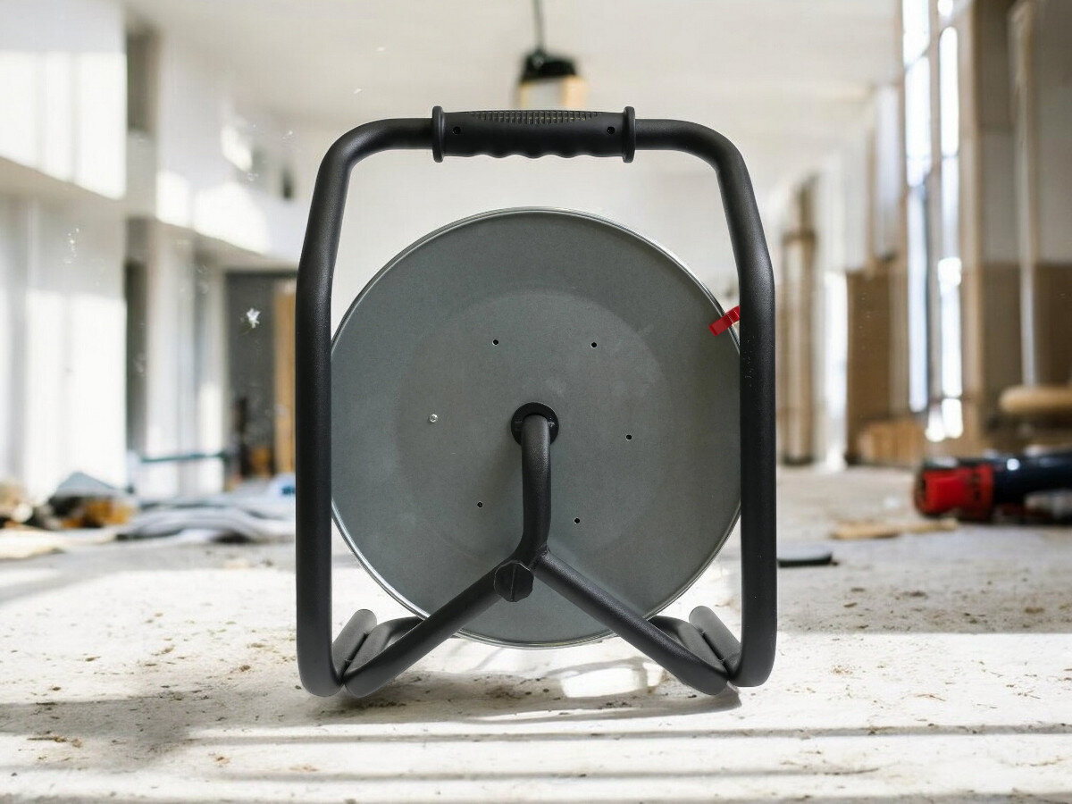 Przedłużacz bębnowy BORBY BY-02-36577 (50 m), ochrona, wyłącznik, IP44, wygoda, przedłużacz od tyłu pionowo frontem na wprost, w tle trwająca prace remontowo-budowlane