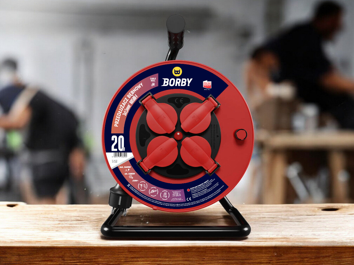 Przedłużacz bębnowy BORBY BY-02-36591 (20 m), solidne, odległość, zasięg, dystans, przedłużacz frontem na wprost z 4 wejściami stoi, w tle trwają prace remontowo-budowlane