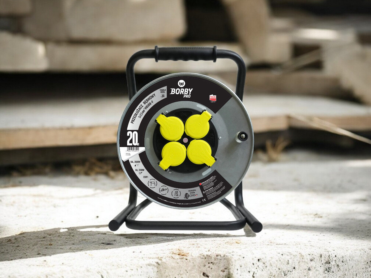 Przedłużacz bębnowy BORBY BY-02-36492 (20 m), solidne, odległość, zasięg, dystans, przedłużacz frontem na wprost z 4 wejściami stoi, w tle trwają prace remontowo-budowlane