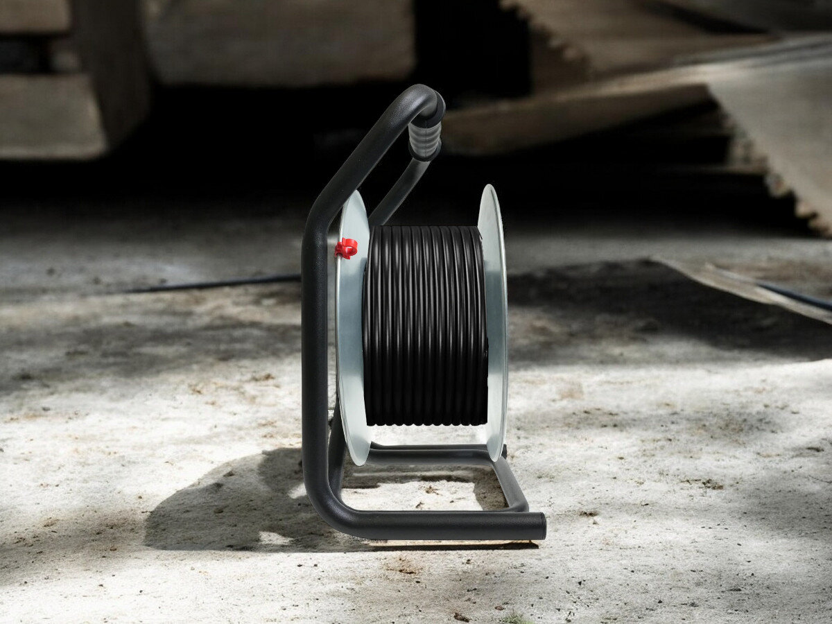 Przedłużacz bębnowy BORBY BY-02-36492 (20 m), praca, przewód, gniazda, trwałość, przedłużacz od boku frontem na wprost z nawiniętym kablem, w tle trwają prace remontowo-budowlane