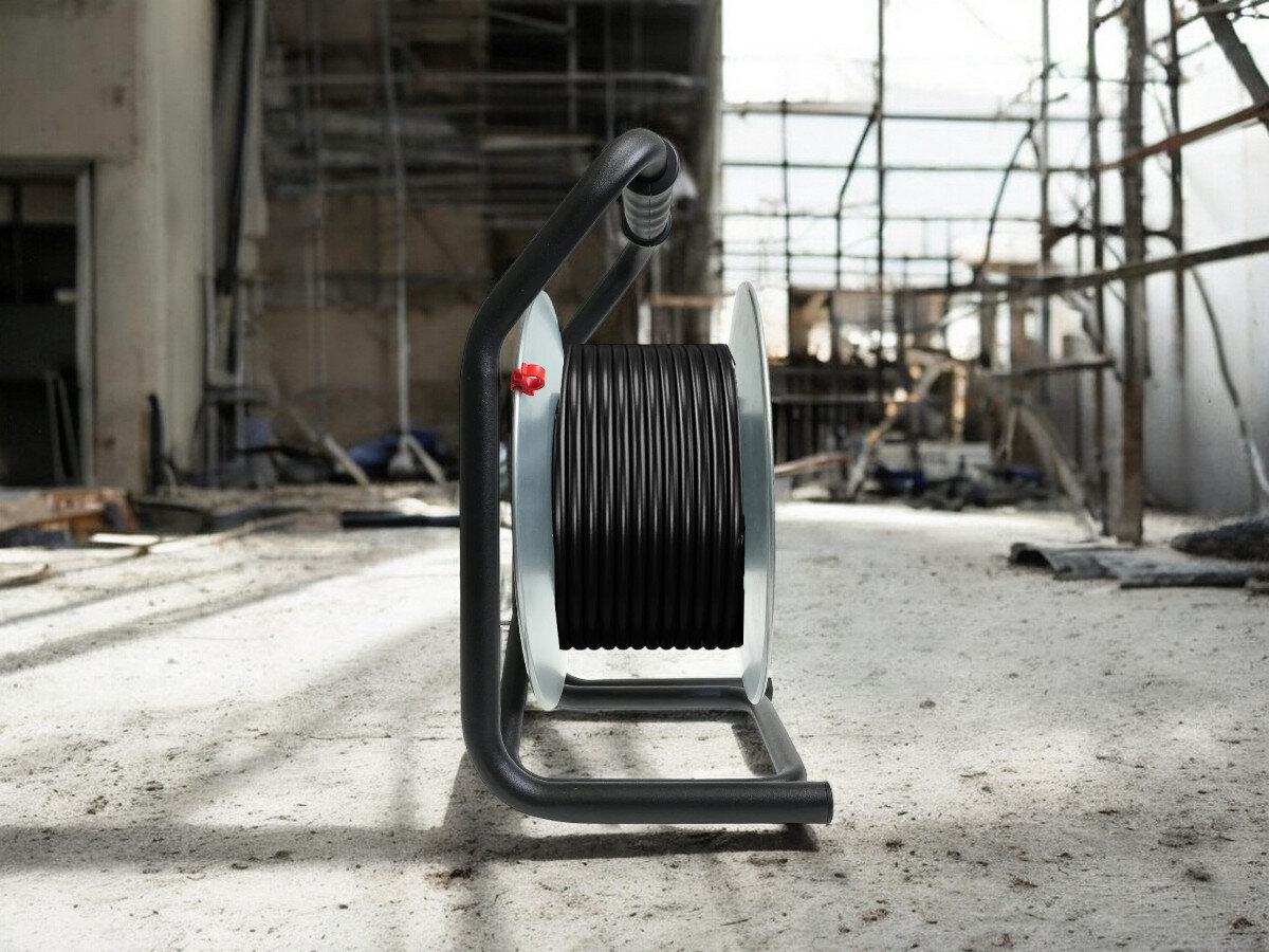 Przedłużacz bębnowy BORBY BY-02-36515 (25 m), praca, przewód, gniazda, trwałość, przedłużacz od boku frontem na wprost z nawiniętym kablem, w tle trwają prace remontowo-budowlane