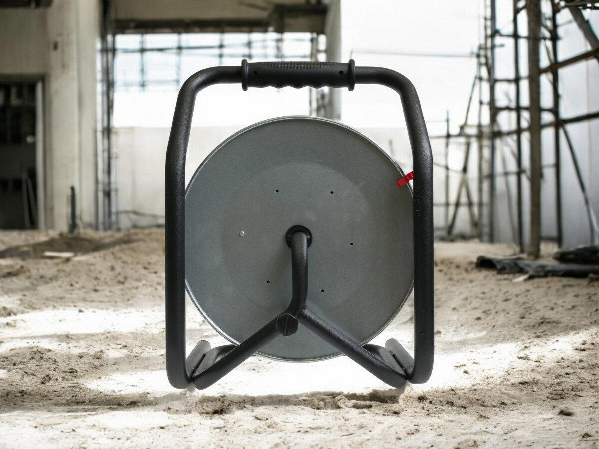 Przedłużacz bębnowy BORBY BY-02-36515 (25 m), ochrona, wyłącznik, IP44, wygoda, przedłużacz od tyłu pionowo frontem na wprost, w tle trwająca prace remontowo-budowlane