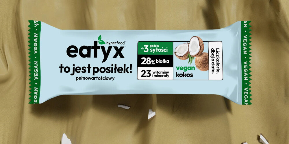 Baton proteinowy EATYX Hyperfood Kokosowy (8 x 60 g) baton na jasnobrązowym tle wokół skorupki kokosa posiłek pełnowartościowy baton