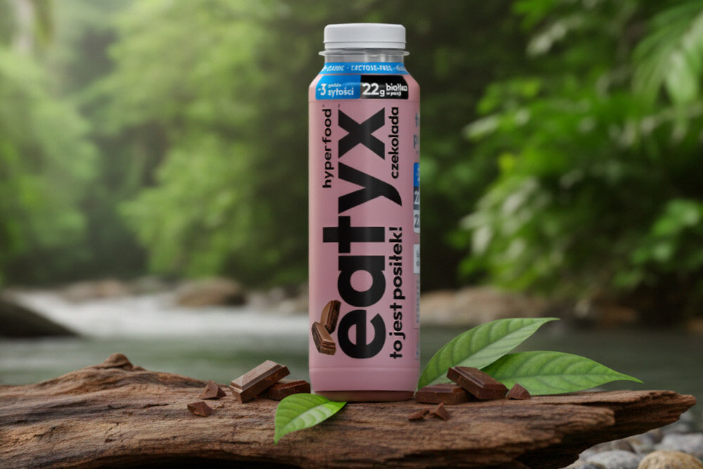 Posiłek w płynie EATYX Hyperfood Czekoladowy (300 ml) butelka stoi na drewnianej kłodzie rozmazane zielone tło olej słonecznikowy źródło kwasów omega-6 i witaminy E chroni komórki przed stresem oksydacyjnym oraz wspiera serce, skórę i odporność węglan wodorotlenku magnezu magnez niezbędny dla kości, mięśni i układu nerwowego