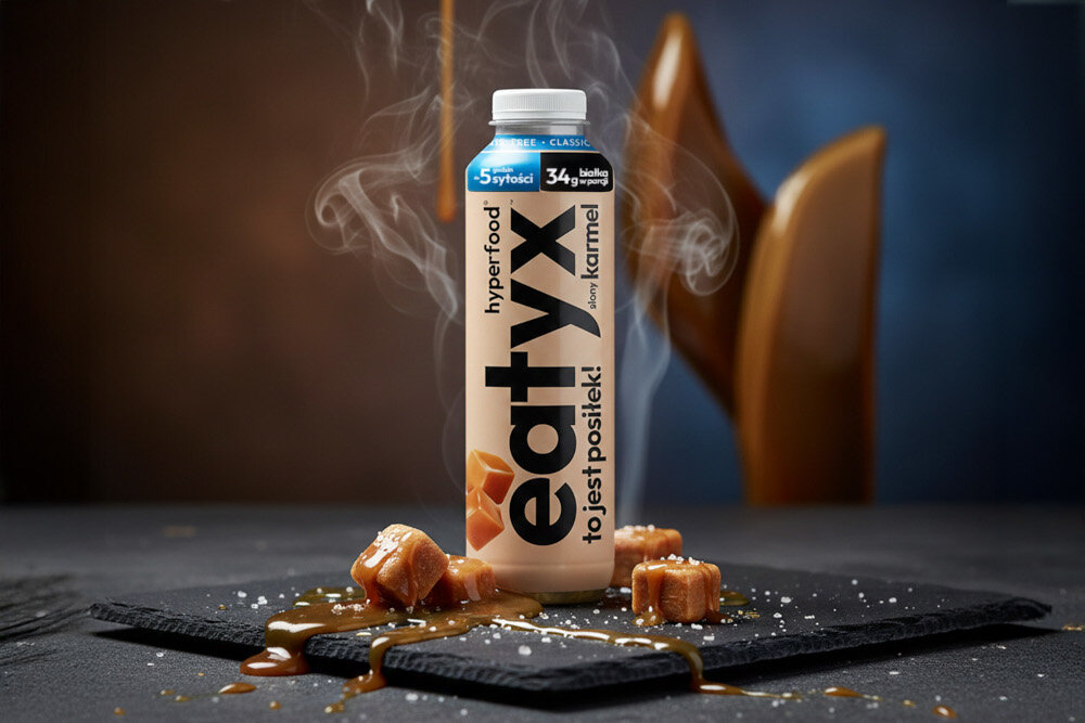 Posiłek w płynie EATYX Hyperfood Słony Karmel (500 ml) ciemne tło butelka ustawiona na czarnym płaskim kamieniu wokół butelki leżą kostki karmelu posiłek w płynnie zbilansowany posiłek zdrowie