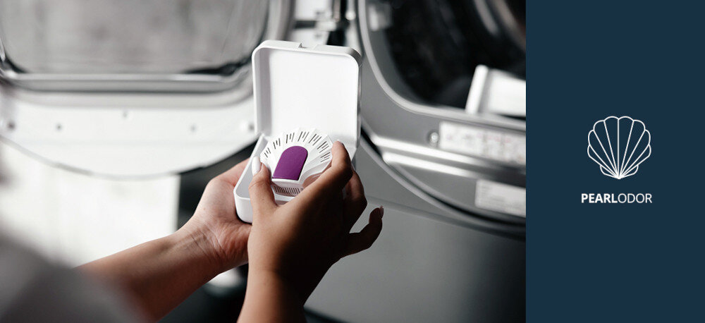 Suszarka VESTFROST VT-FD4EHY70EU Na zdjęciu widoczne są dłonie osoby trzymającej pojemnik z wkładką zapachową Pearl Odor do suszarki Vestfrost, na tle otwartych drzwiczek urządzenia. Po prawej stronie znajduje się grafika informująca o systemie odświeżania bębna suszarki Pearl Odor PearlOdor wkład zapachowy świeży zapach ubrań zapach podczas suszenia odświeżanie tkanin Vestfrost zapach ubrań