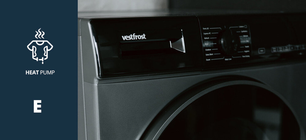 Suszarka VESTFROST VT-FD4EHY70EU Na zdjęciu pokazano fragment panelu sterującego suszarki marki Vestfrost, uchwycony z bliska w wnętrzu. Po lewej stronie widnieje grafika informująca o technologii pompy ciepła Heat Pump oraz klasie energetycznej E pompa ciepła energooszczędna niskotemperaturowa klasa energetyczna E ochrona tkanin delikatne suszenie oszczędna Vestfrost pompa ciepła