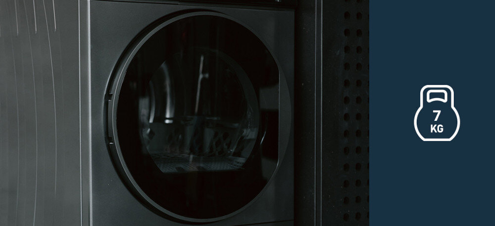 Suszarka VESTFROST VT-FD4EHY70EU Na zdjęciu znajduje się suszarka bębnowa Vestfrost w ciemnym kolorze, przedstawiona z bliska na tle ciemnej ściany. Po prawej stronie grafika informuje o maksymalnej pojemności urządzenia wynoszącej 7 kg kompaktowa do mieszkania do małej łazienki slim 45 cm dla małej rodziny Vestfrost 7 kg