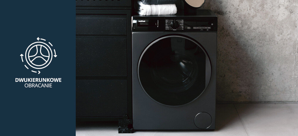 Suszarka VESTFROST VT-FD4EHY70EU Na zdjęciu znajduje się suszarka Vestfrost o ciemnym froncie, ustawiona we wnętrzu z betonu i czarną zabudową. Po lewej stronie widnieje grafika wskazująca na funkcję dwukierunkowego obracania bębna, która pozwala równomiernie i skutecznie suszyć odzież dwukierunkowe obracanie bębna równomierne suszenie brak zbijania się ubrań przeciw skręcaniu ubrań równy efekt suszenie bez wilgotnych miejsc