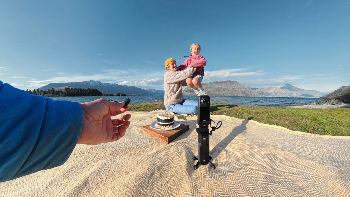 INSTA360 X4 Air X4 Air kamera 360° kamera sportowa dynamicznych ujęć z perspektywy pierwszej osoby 4K 60 kl./s szerokim polem widzenia 170° FreeFrame Video 4K 30 kl./s post produkcji kąt widzenia współczynnik proporcji. - Scena urodzinowa z dzieckiem i kamerą na statywie na tle jeziora i gór