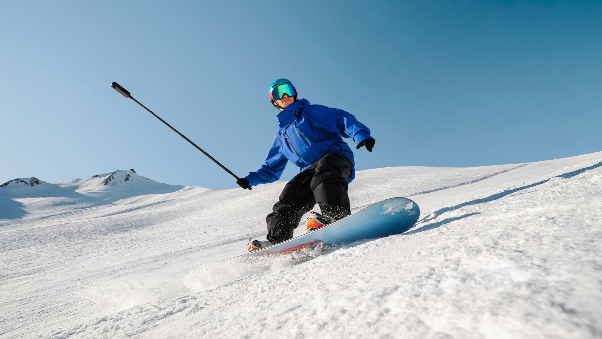 INSTA360 X4 Air Stabilizacja obrazu automatyczne poziomowanie horyzontu stabilne nagrywaniu 360° oraz 6-osiowemu żyroskopowi - Snowboardzista w czarno-niebieskiej kurtce z kamerą na białym stoku górskim