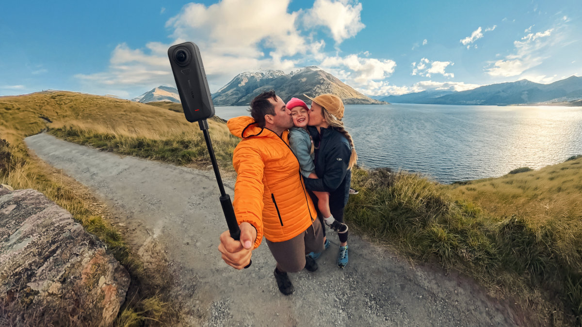 INSTA360 X4 Air Podwójne obiektywy jakości 8K 30 kl./s edycji odpowiedni kadr Insta360 X4 Air aplikacji Insta360 narzędziom kadrowania - Para z dzieckiem robiąca selfie kamerą na tle jeziora i gór w słoneczny dzień