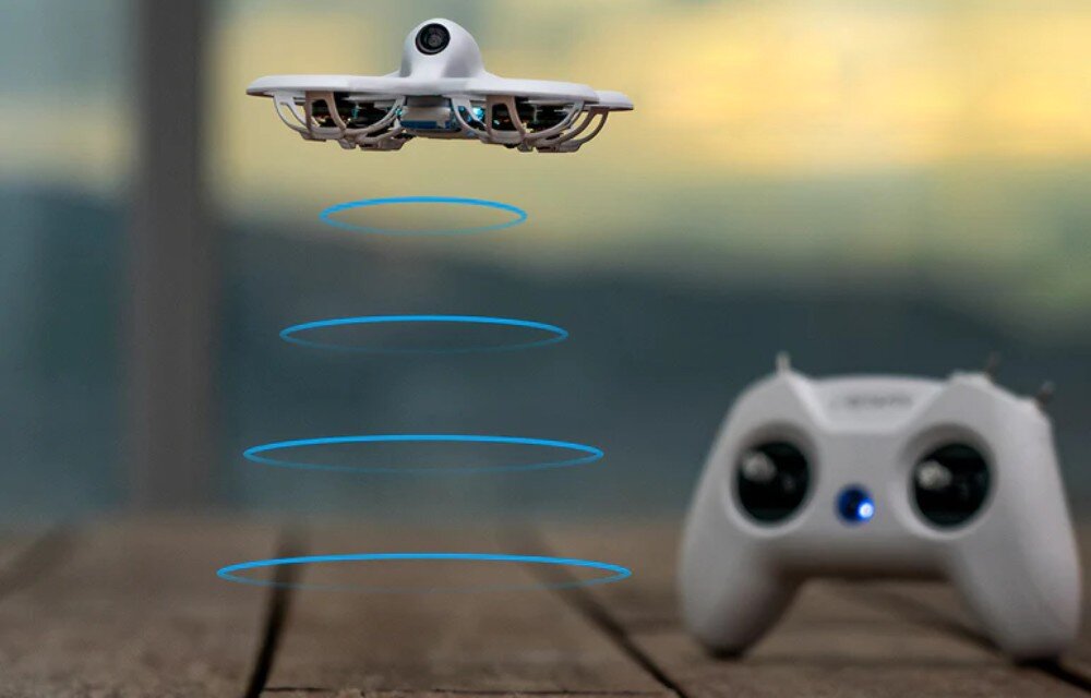 Dron BETAFPV Cetus Pro FPV Kit Dron wykonujący zawis w powietrzu nad drewnianym podłożem z wizualizacją niebieskich okręgów emitowanych przez czujniki pod spodem