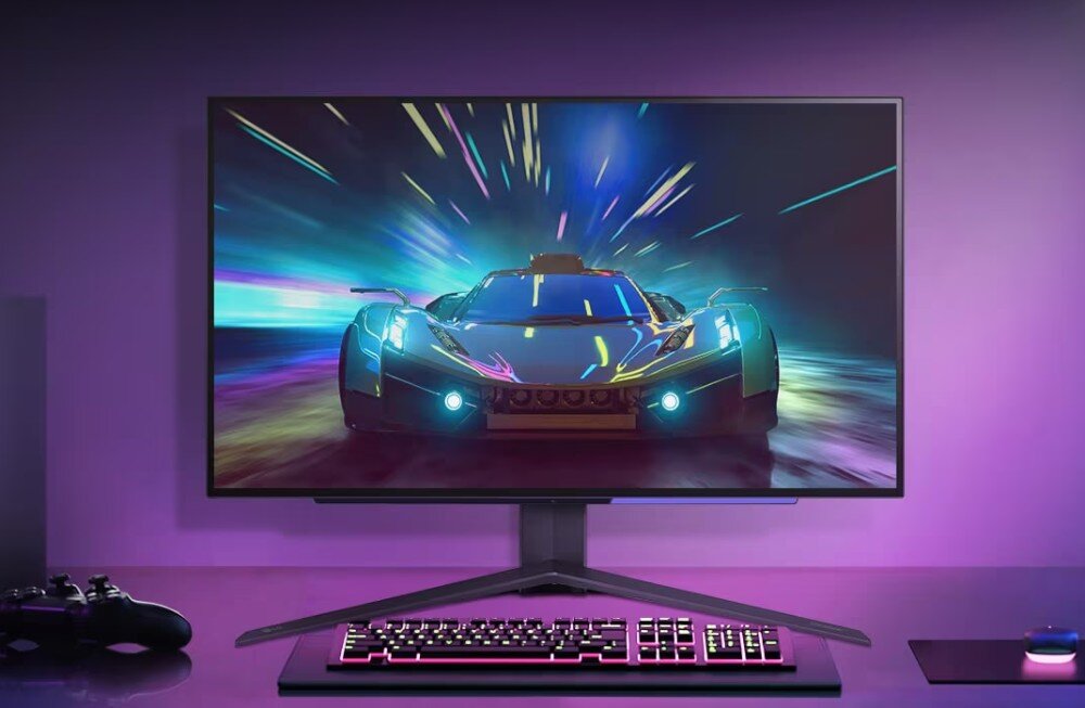 Monitor LG UltraGear 27GS95QE-B.AEU Widok monitora ustawionego na biurku, wyświetlającego grafikę wyścigową. Wokół monitor podświetlenie RGB i gamingowa klawiatura, jasność, HDR